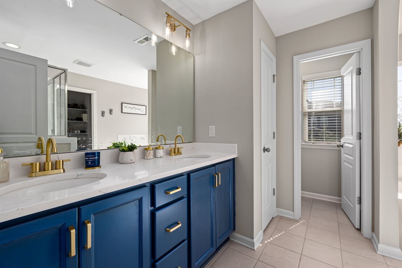 Services-02 Stylish bathroom featuring a blue vanity, gold fixtures, and decorative accents for a modern home interior.
